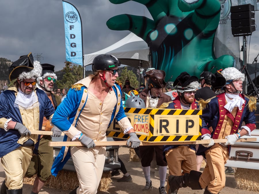 Pallbearers in pirate and colonial costumes charge down the course with a coffin marked "RIP".
