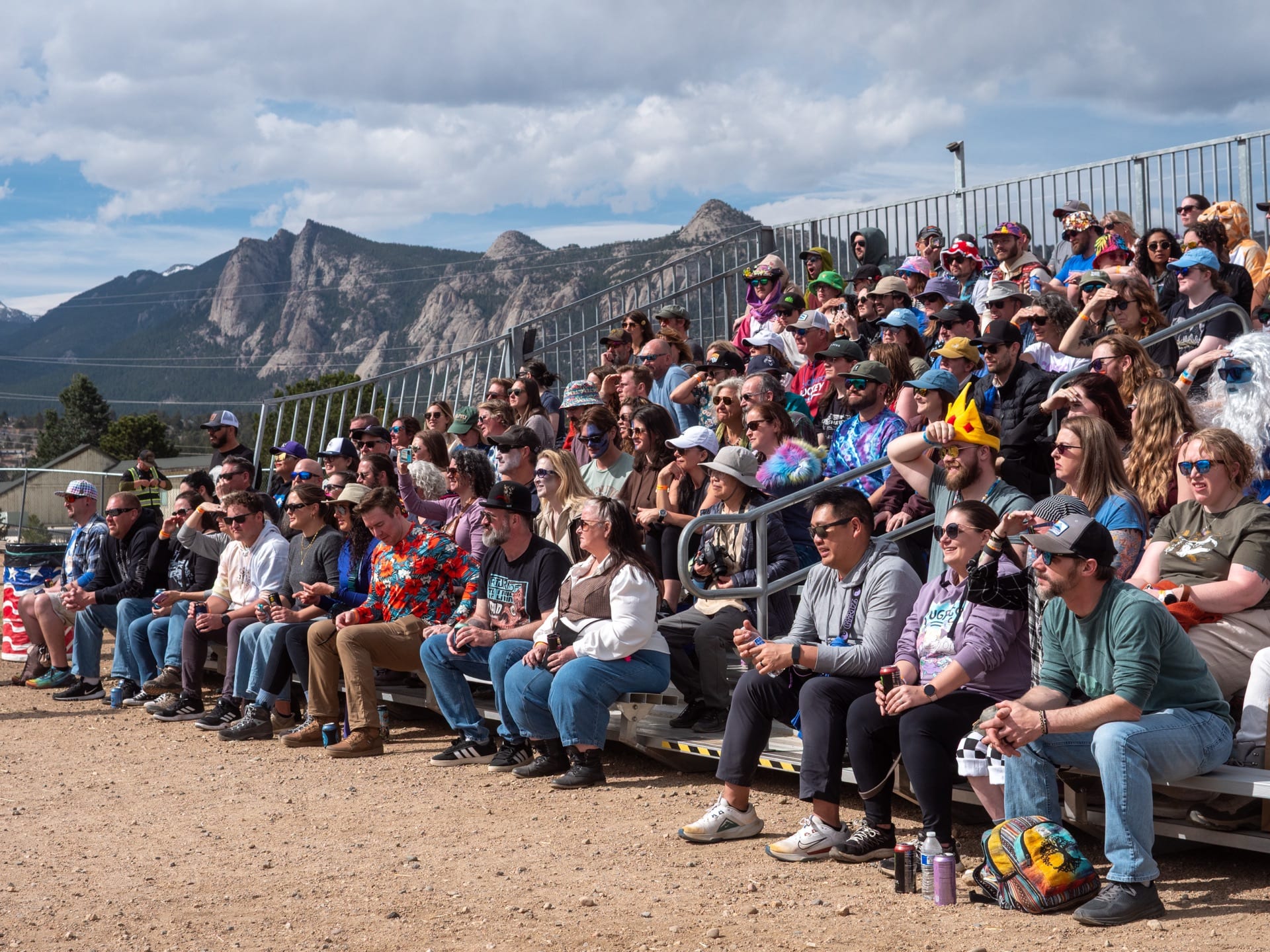A packed grandstand watches the races with rocky peaks behind.