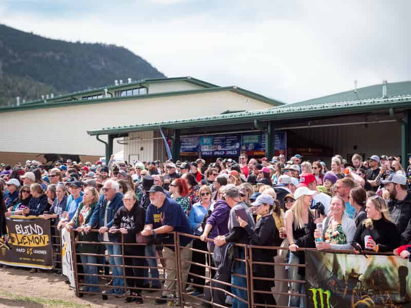 Spectators line the course fence in front of the Events Complex barns and mountains.