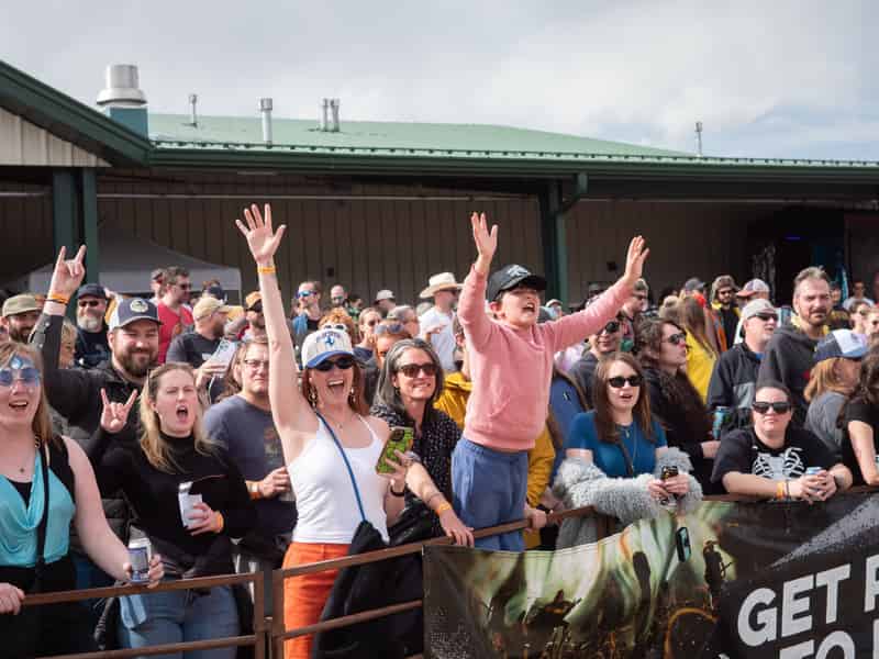 Fans throw their arms up and cheer at the course fence.