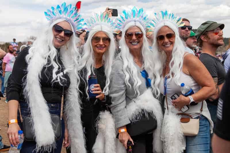 Four friends in matching white wigs and ice-queen costumes pose in the crowd.