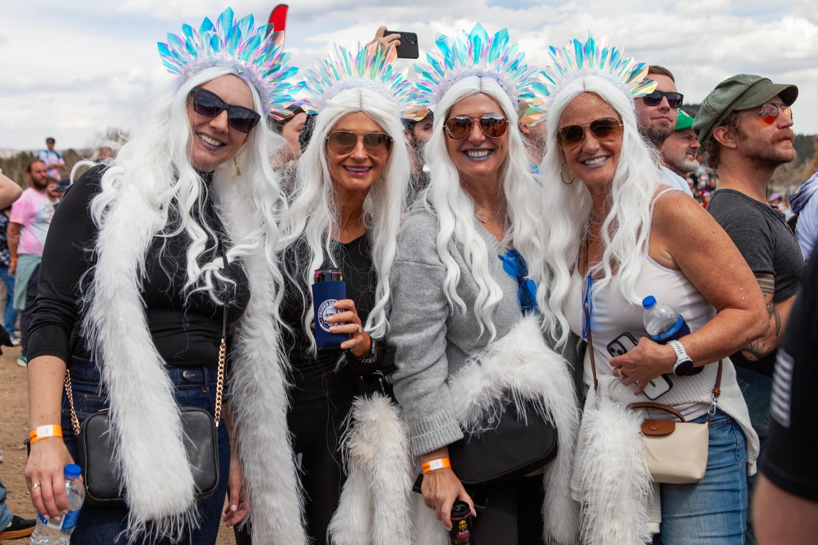 Four friends in matching white wigs and ice-queen costumes pose in the crowd.