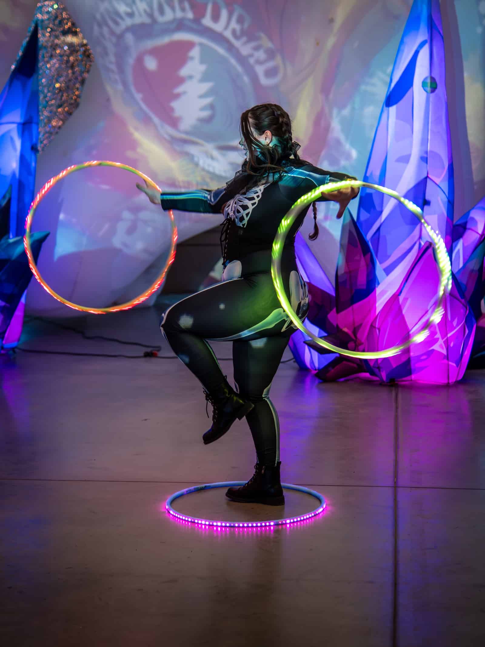 An LED hoop dancer performs on a glowing stage.