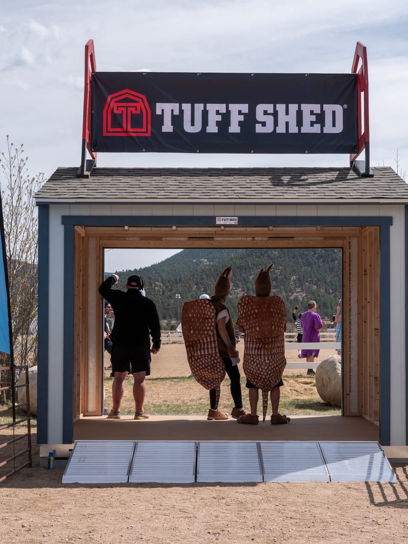 A Tuff Shed display on the festival grounds, with costumed guests inside.