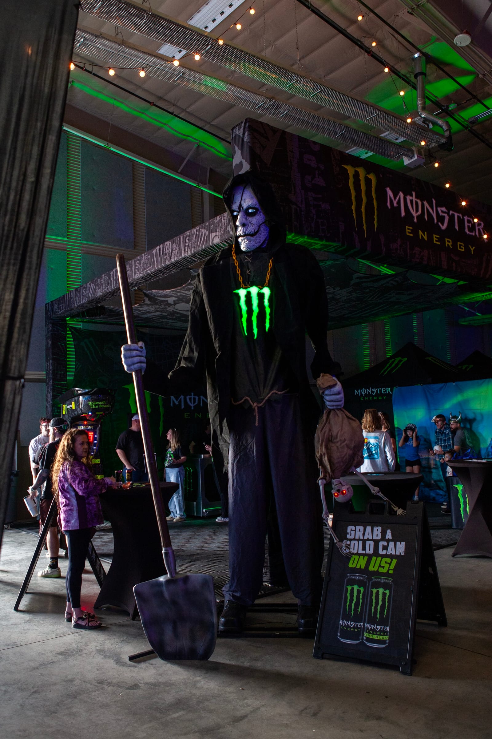 A towering grim-reaper figure stands in the Monster Energy area.