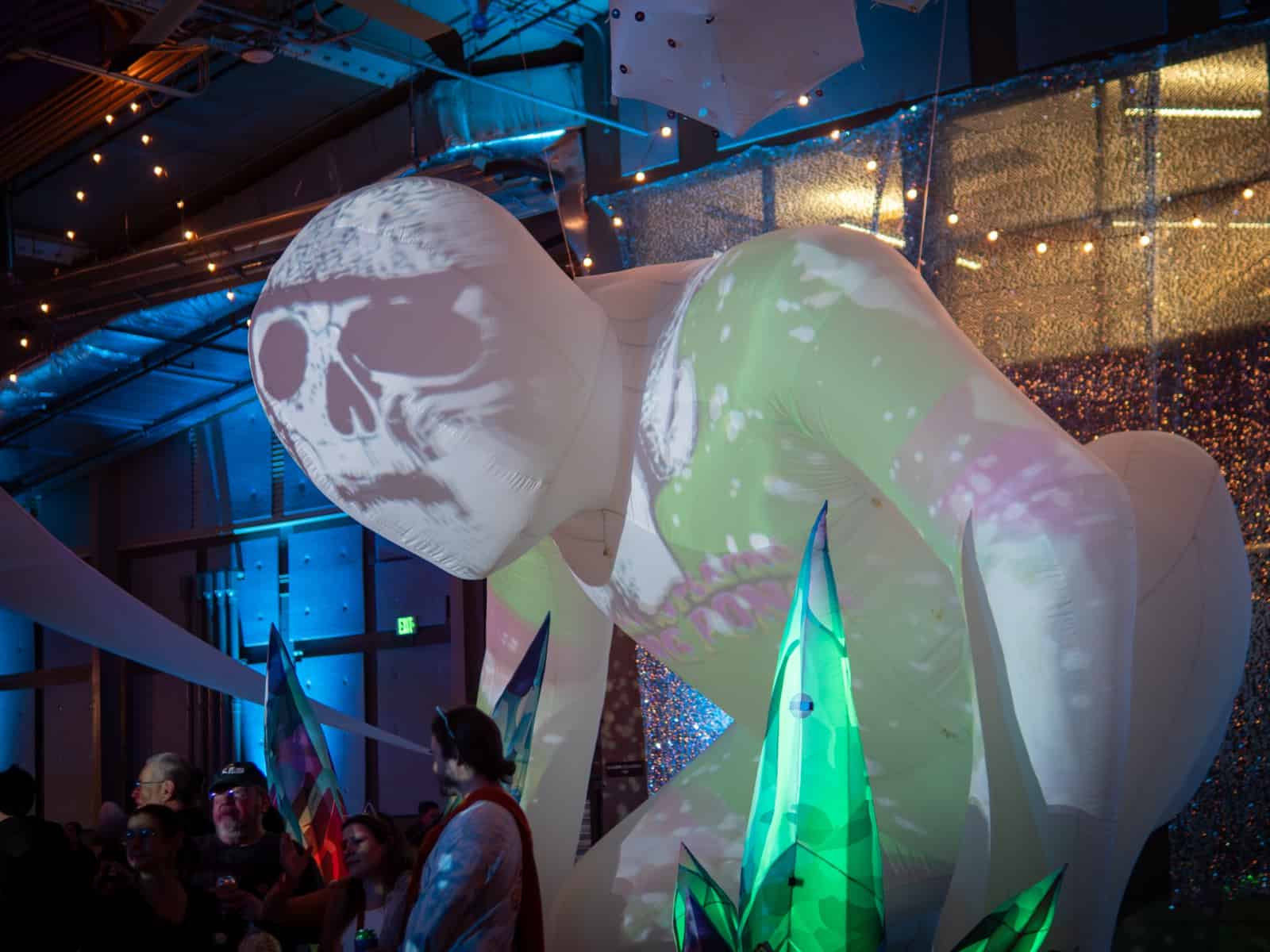 A giant inflatable skull glows under blue lights inside the festival hall.