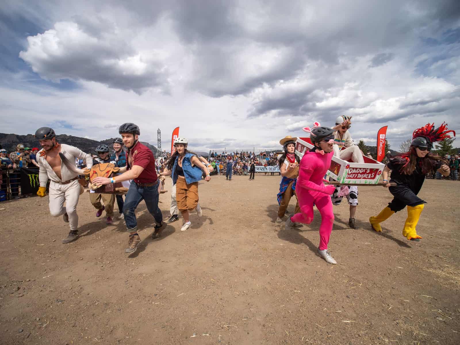 Racers dressed as a pink pig, a cow and a rooster sprint with their painted coffin across the course.