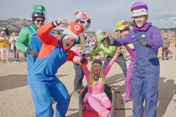 Border Burger Bar, dressed as Mario, Luigi, Wario, Waluigi, Toad and Yoshi, cheer at the start with Princess Peach riding in their kart-style coffin, the festival skull sign behind.