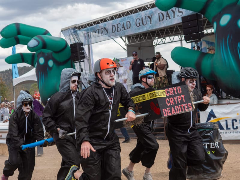 The Cryo Crypt Deadites, in black jumpsuits and pale corpse makeup, carry their coffin in front of the stage's giant green hands.