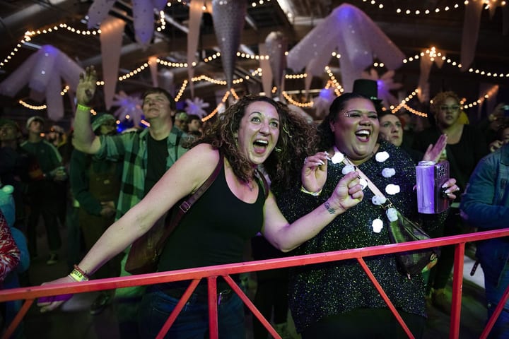 Two women scream with joy at the front rail.