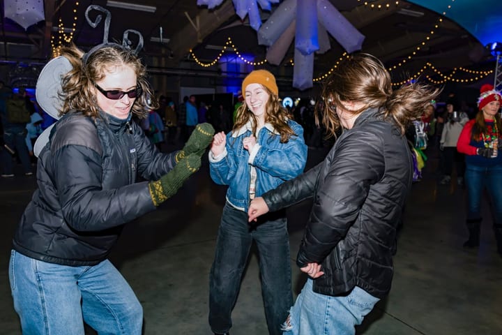 Three women dance together on the floor.
