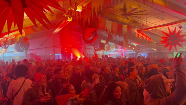 A packed Fire hall dances under red and orange spiky inflatables and haze.
