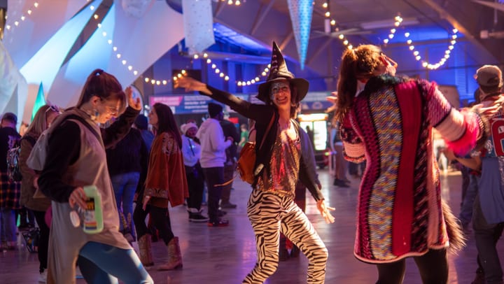 Costumed dancers fill the hall under string lights and ice-crystal decor at night.