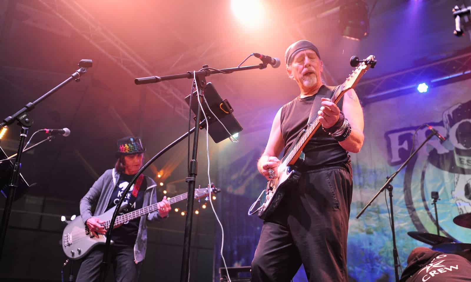 A guitarist in a headband plays under pink and blue stage lights before the Frozen backdrop.