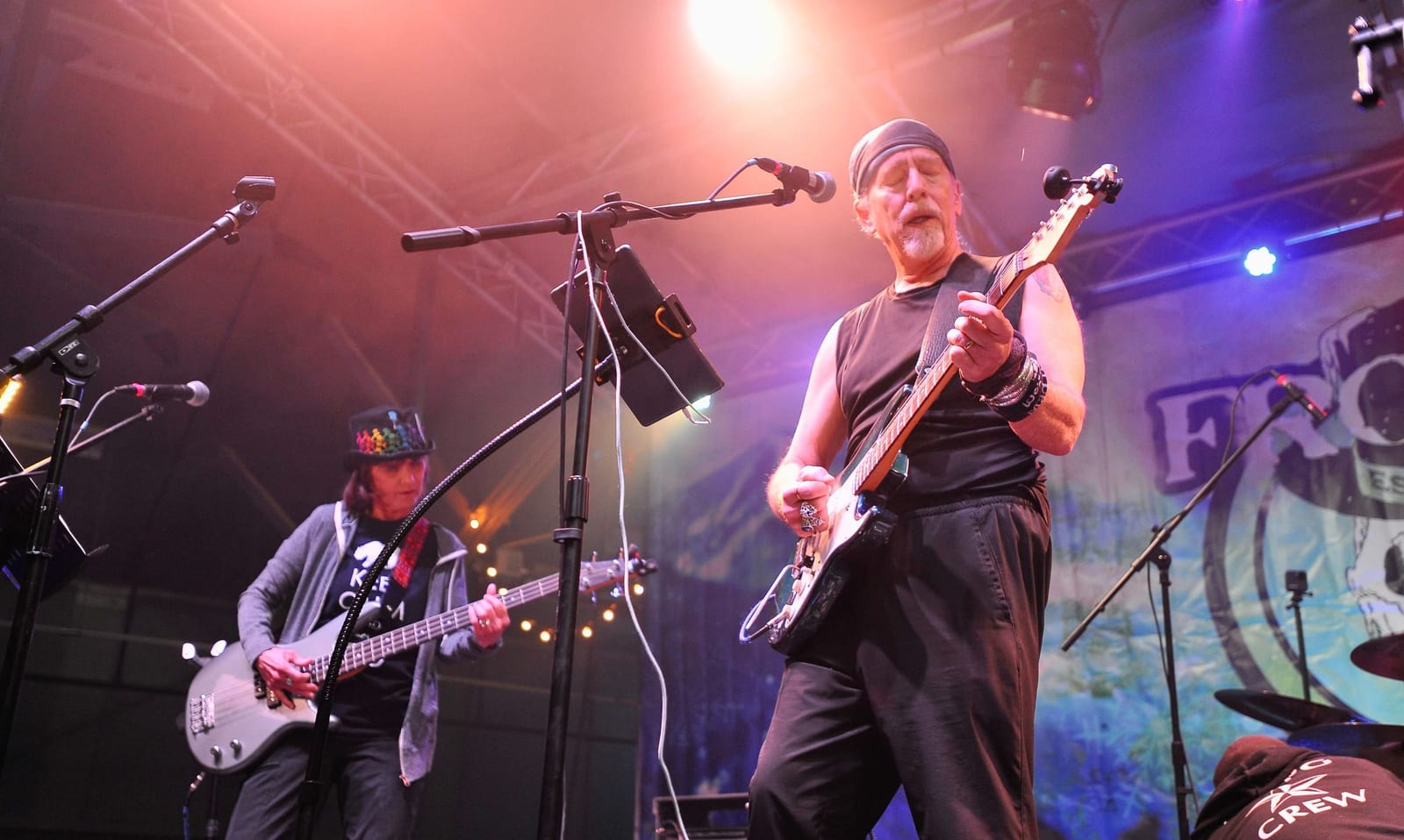 A guitarist in a headband plays under pink and blue stage lights before the Frozen backdrop.