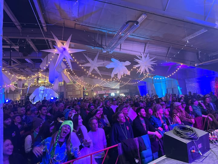 A packed crowd dances under star lanterns and string lights in the hall.
