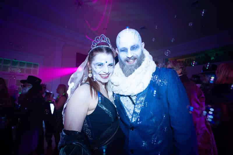 A laughing bride in a tiara and veil and a frosted, bearded ice groom at The Frozen Blue Ball.