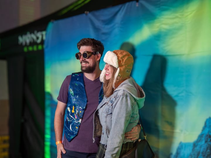 A couple poses in front of the glowing Monster Energy backdrop.