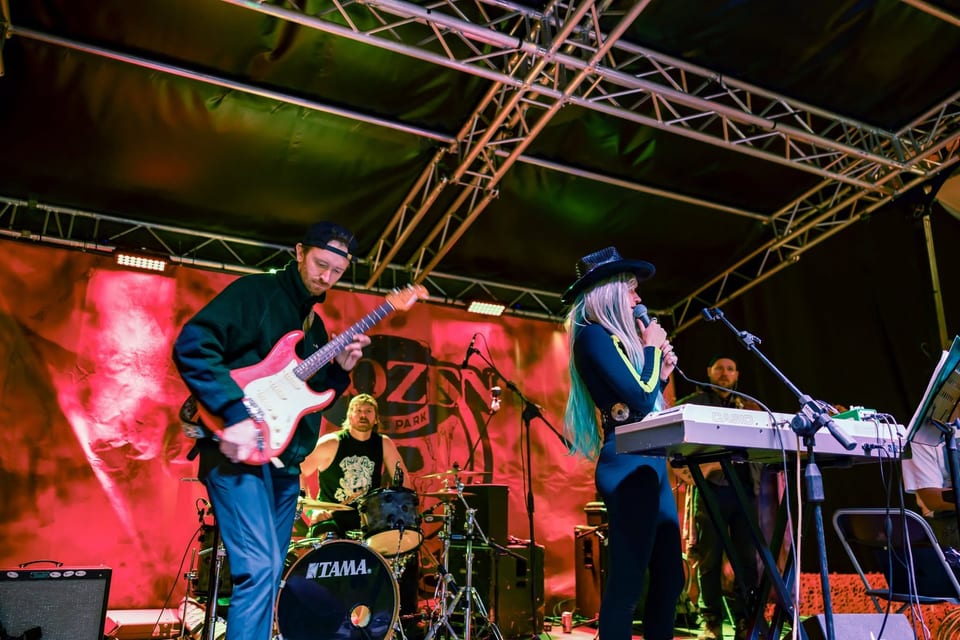 A guitarist, a drummer and a singer in a cowboy hat at the keys play the red-lit Fire stage.