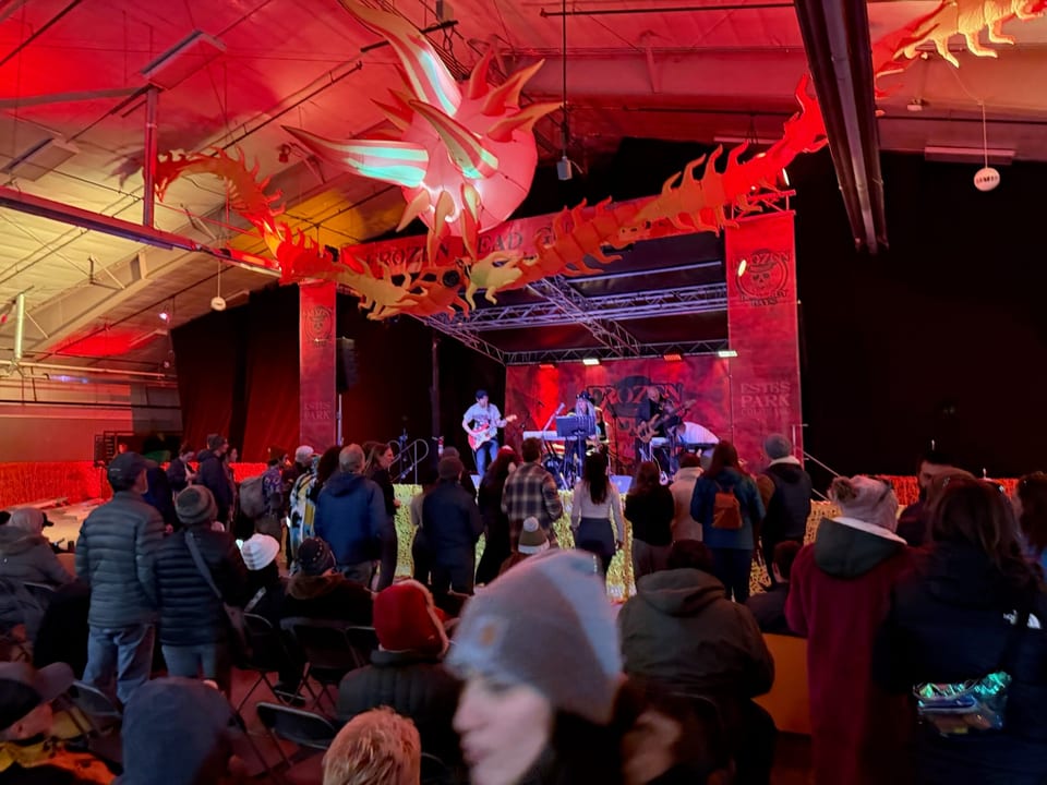 A band plays a red-lit stage under paper flames as the crowd stands and watches.
