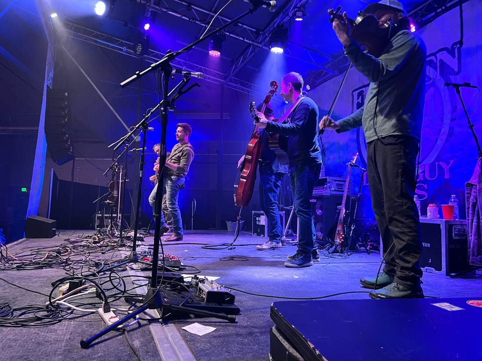 Fiddle, upright bass and guitars on the Ice stage in blue light.